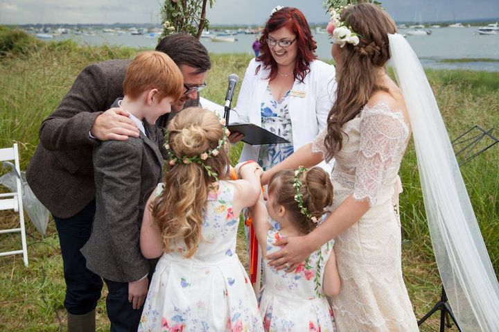 A bride and groom hugging their children during the ceremony at West Mersea